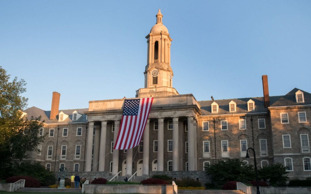 large American flag hanging from top of Old Main